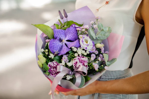 Manos de mujer sosteniendo una composición púrpura de flores —  Fotos de Stock