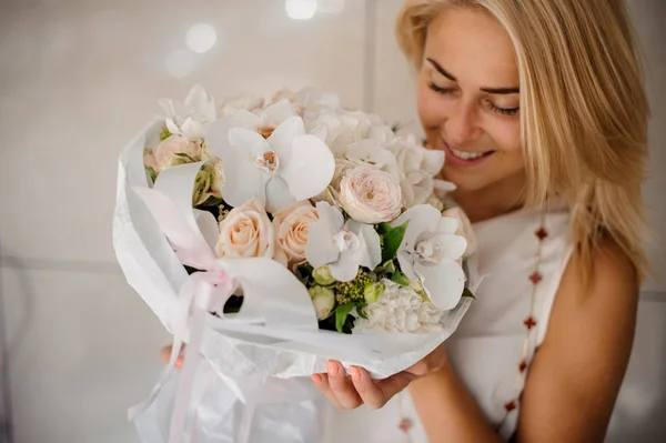 Jeune femme souriante tenant une composition de fleurs — Photo