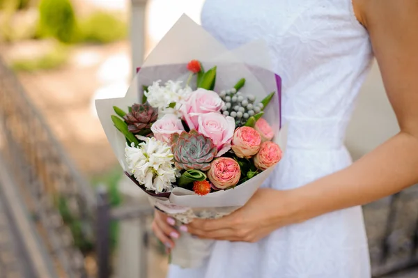 Mãos de mulher com uma pequena composição rosa de flores — Fotografia de Stock