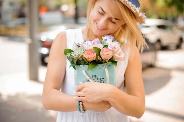 Donna sorridente in abito bianco con un cesto di fiori di vimini — Foto Stock