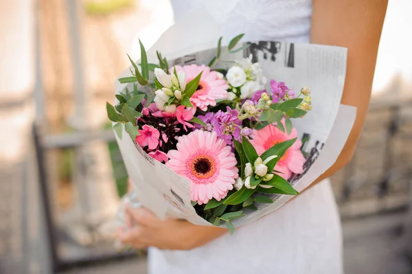 Mulher de vestido branco segurando um lindo buquê de flores — Fotografia de Stock