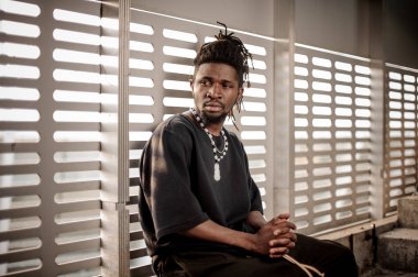 Pencere pervazına üzerinde oturan Afro Amerikan adam