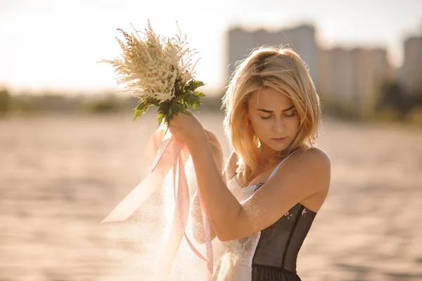 Attraente donna bionda con fiori in mano — Foto Stock