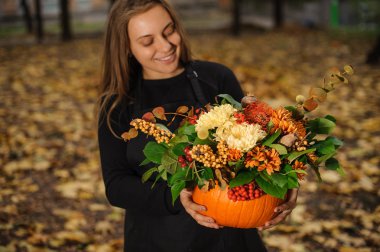 Çiçekçi bir kabak ile sonbahar çiçek tutan gülümseyerek