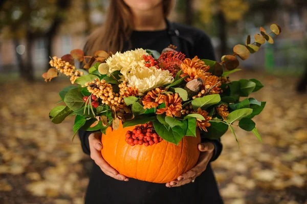 Pumpkin with beautiful bouquet of autumn flowers in woman hands — Stock Photo, Image
