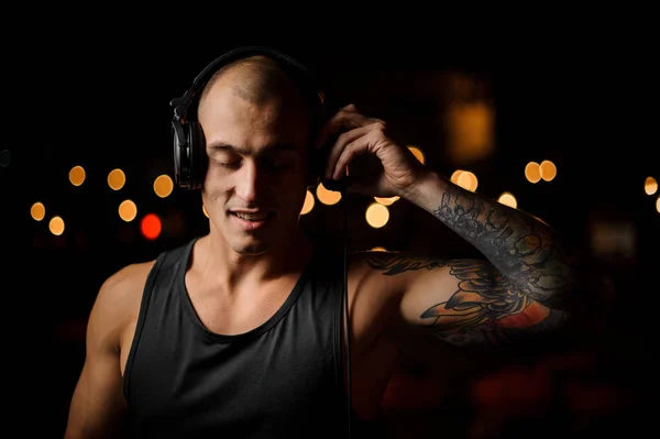 DJ en auriculares siente la música en el fondo de las luces del club nocturno — Foto de Stock