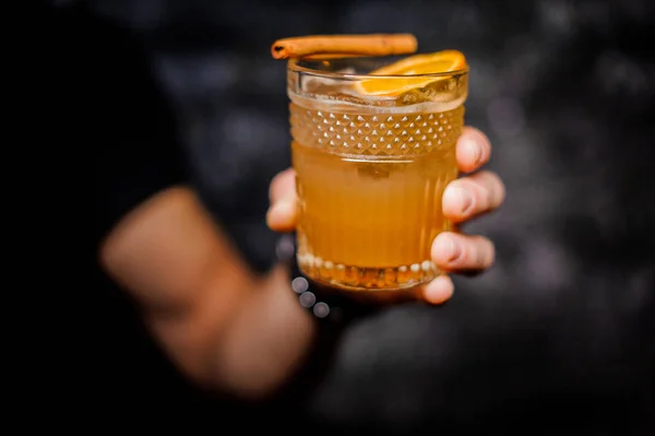 Male hand holding a glass of fresh orange alcoholic drink — Stock Photo, Image