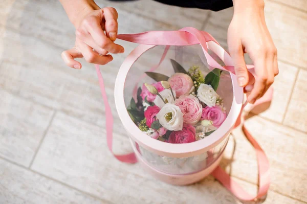 Вид сверху на руки и стильная цветочная коробка с розовой лентой — стоковое фото