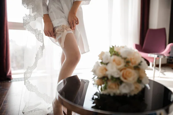Nevěsta, oblékat krásné bílé punčochy na nohách — Stock fotografie