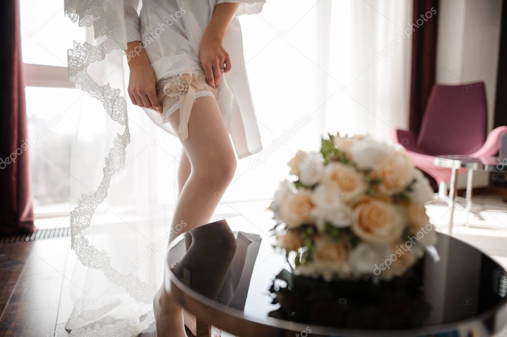 Bride dressing beautiful white stockings on feet