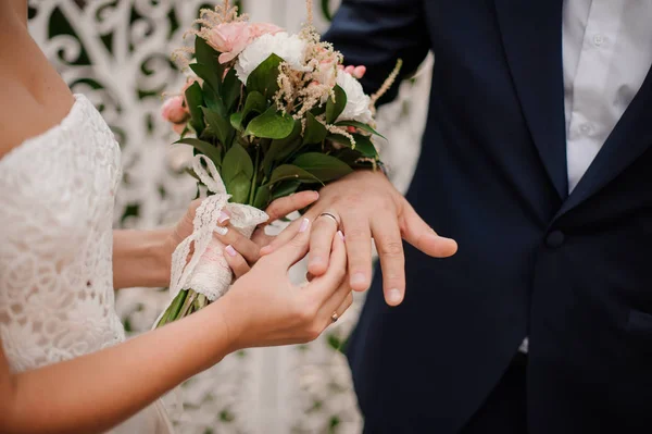Recién casados intercambiando anillos, novia poniendo el anillo en la mano del novio — Foto de Stock