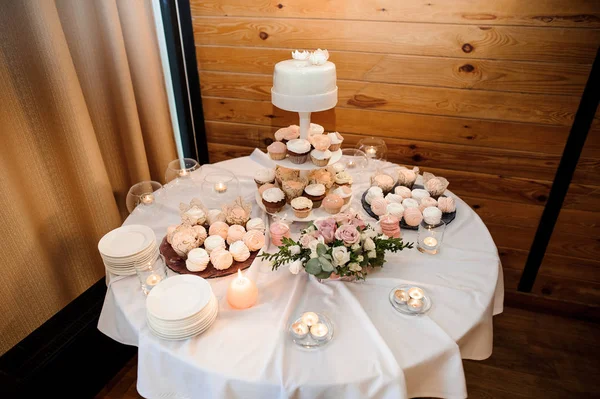 Table ronde couverte d'une nappe blanche et servie avec des gâteaux — Photo