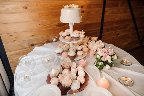 Mesa redonda cubierta con un mantel blanco, decorada con velas y servida con pasteles —  Fotos de Stock