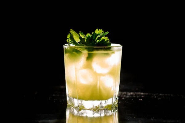 Vaso de bebida alcohólica fresca con hielo decorado con hojas de perejil — Foto de Stock