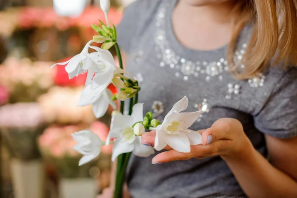 Mujer en un vestido gris sosteniendo unas hermosas flores blancas — Foto de Stock