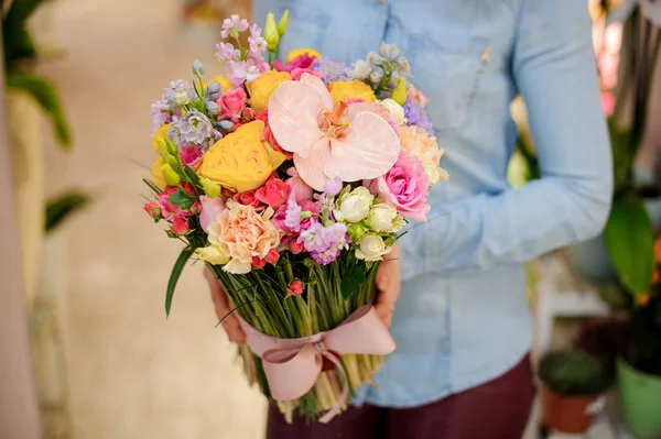 Floristería sosteniendo un hermoso ramo colorido de flores con un lindo lazo —  Fotos de Stock