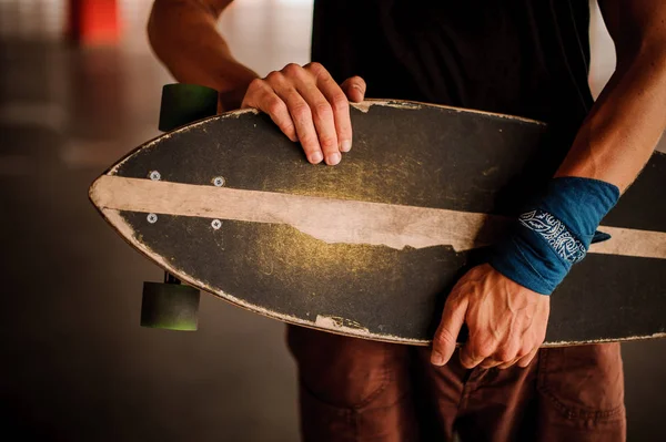 Ung man med en armbindel som innehar en longboard — Stockfoto