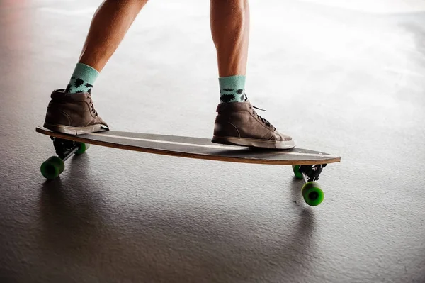 Mans benen in sneakers staande op een longboard — Stockfoto