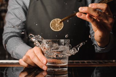 Barmans el alkollü içki sıçramasına cam içine bir dilim limon ekleme