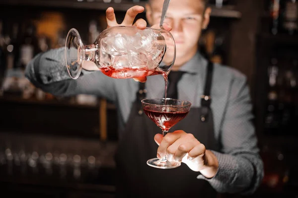 Barman derramando um coquetel vermelho alcoólico no copo — Fotografia de Stock