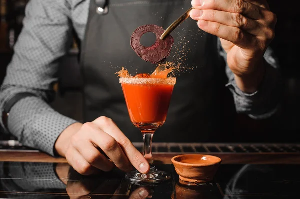 Barman em um avental cinza decorando um copo de coquetel alcoólico — Fotografia de Stock