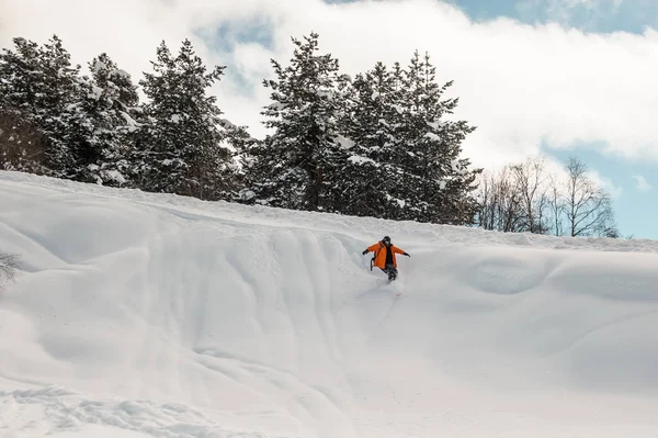 Cavaleiro de snowboard descendo a encosta de neve — Fotografia de Stock