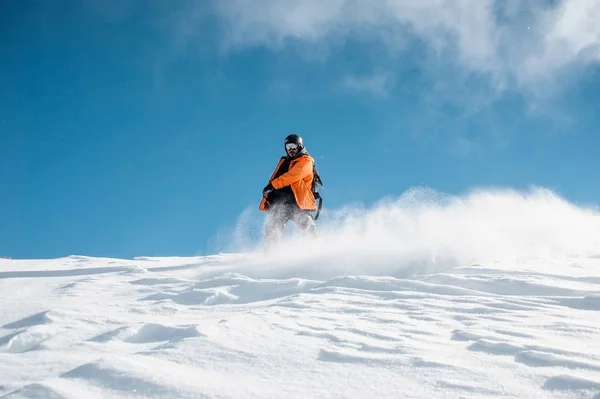 Snowboarder en ropa deportiva naranja cabalgando por la colina de nieve en polvo —  Fotos de Stock