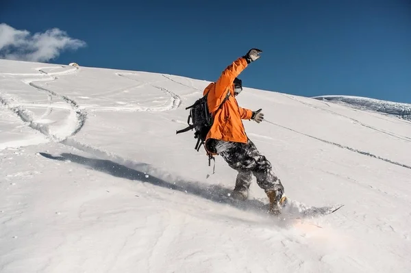Snowboarder em sportswear laranja montando na bela encosta de neve — Fotografia de Stock