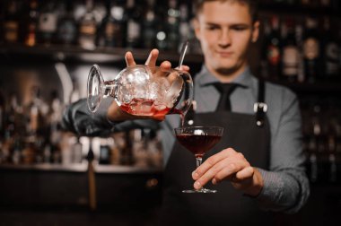 Genç barmen alkollü içki kokteyl cam içine dökme
