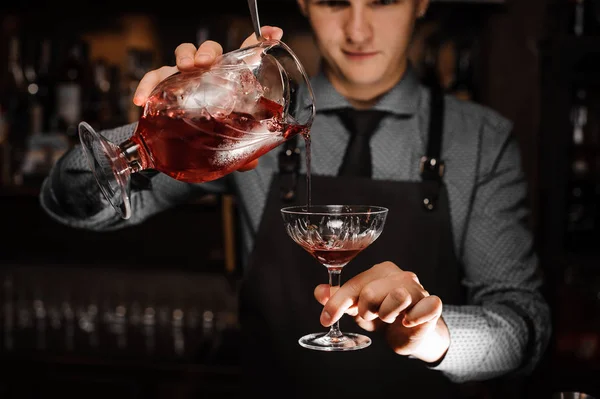 Młody mężczyzna barman leje odświeżające koktajle alkoholowe do kieliszka koktajlowego — Zdjęcie stockowe