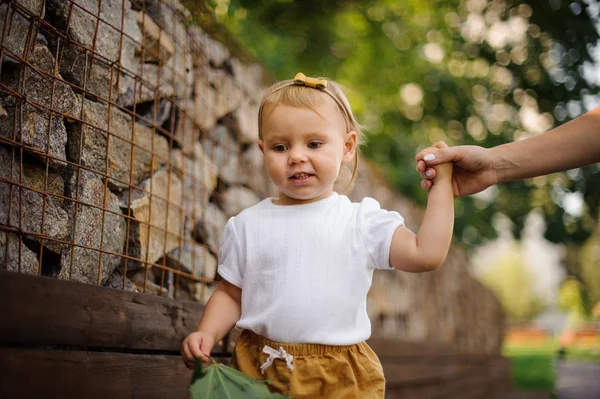 Roztomilá holčička chodí s pomocí matky s rukou — Stock fotografie