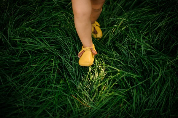 Χαριτωμένο μικρό παιδί πόδια το περπάτημα στο φρέσκο πράσινο γρασίδι — Φωτογραφία Αρχείου