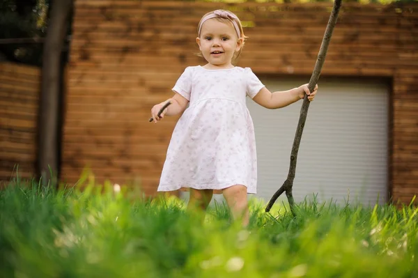 Söta lilla flicka klädd i söt rosa klänning gå på gräset — Stockfoto