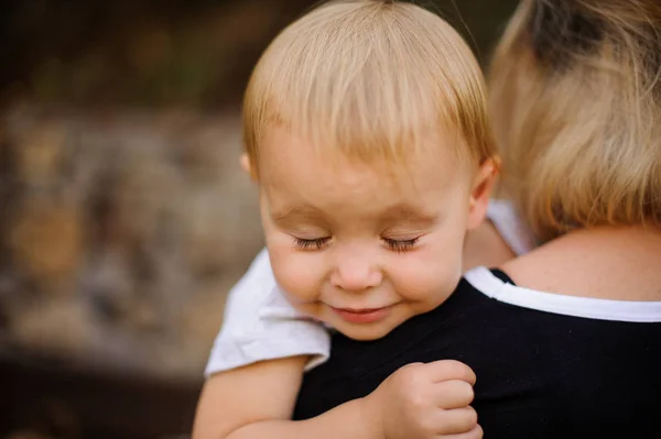 Pequena criança loira deitada no ombro da mãe com os olhos fechados — Fotografia de Stock