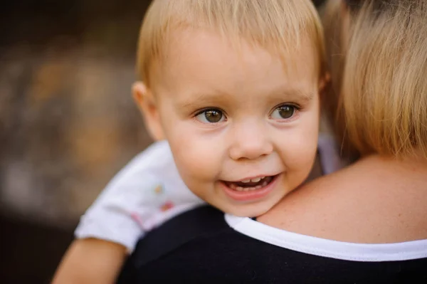 Sorrindo bebê bonito deitado no ombro da mãe — Fotografia de Stock