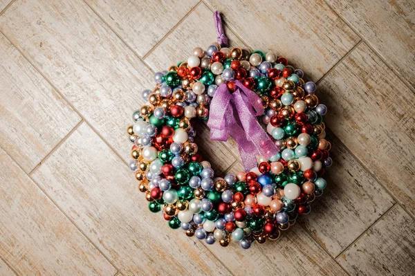 Corona colorida de la decoración de Navidad hecha de bolas y decorada con arco púrpura — Foto de Stock