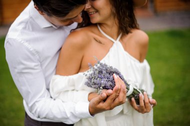 Buket çiçek ile beyaz elbiseli beyaz gömlek sarılma gülümseyen gelin damat