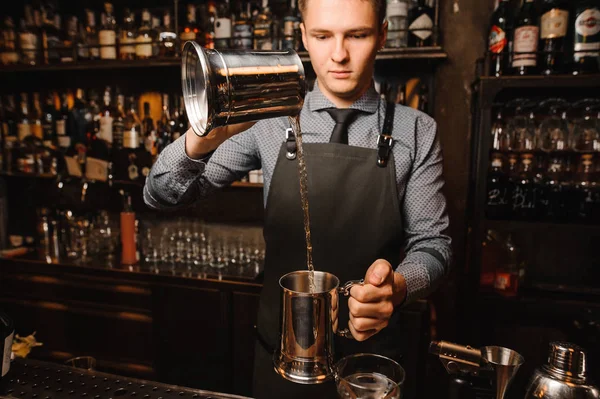 Junger Barmann gießt alkoholisches Getränk von einem Gefäß in ein anderes — Stockfoto