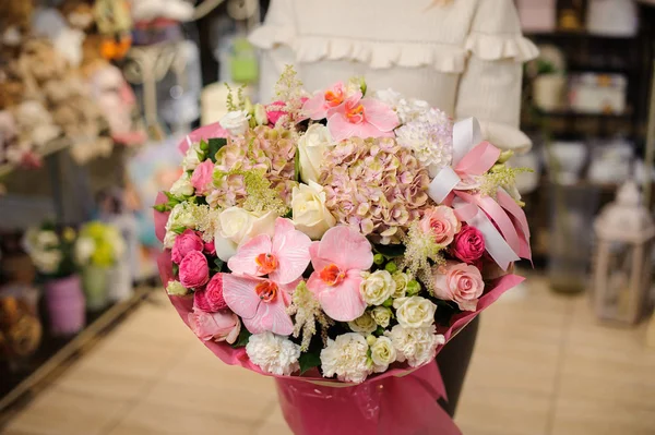 Mulher em uma camisola branca segurando um grande buquê de flores em tons rosa para o dia dos namorados — Fotografia de Stock