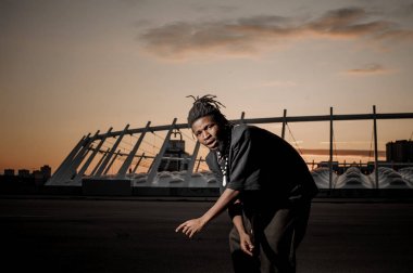 dreadlocks ile Afro-Amerikan erkek günbatımı arka plan üzerinde hareket eder.