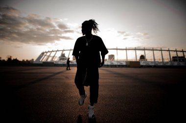 Günbatımı arka plan üzerinde dans dreadlocks ile Afrika adam