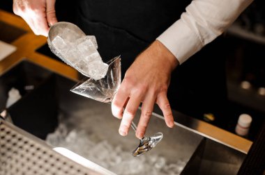 Kokteyl bardağına buz küpleri dökme barmen