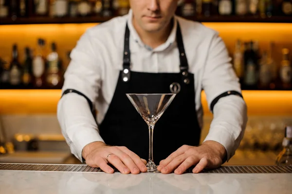 Bartendern i vit skjorta och förkläde med en tydlig och Tom cocktailglas — Stockfoto