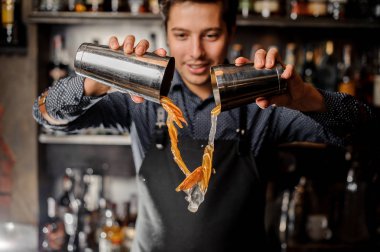 İçki taze turuncu meyve dilimleri ile dökme genç gülümseyen barmen