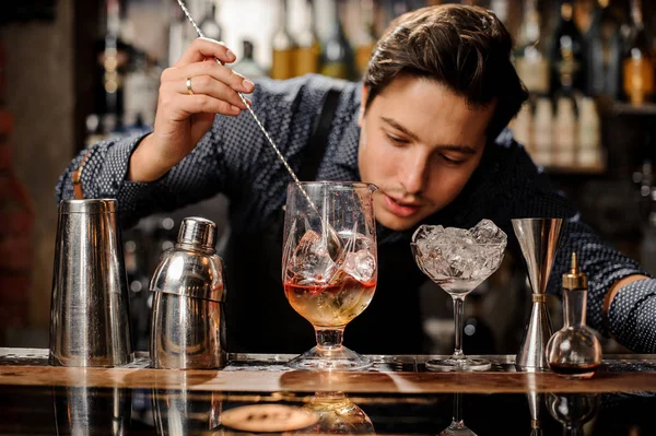 Junger Barmann rührt frischen alkoholischen Cocktail mit Sirup — Stockfoto