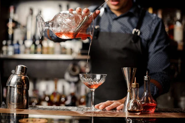 Barman derramando bebida alcoólica vermelha no copo de coquetel — Fotografia de Stock