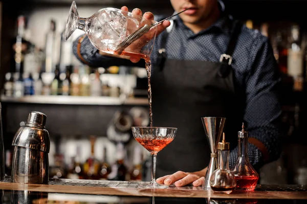 Barman derramando bebida alcoólica vermelha no copo de coquetel — Fotografia de Stock