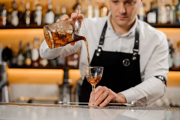Молодой бармен добавляет алкогольный напиток в элегантный бокал — стоковое фото