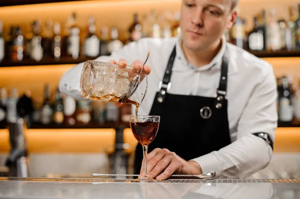 Junger Barkeeper fügt alkoholisches Getränk in ein elegantes Glas hinzu — Stockfoto