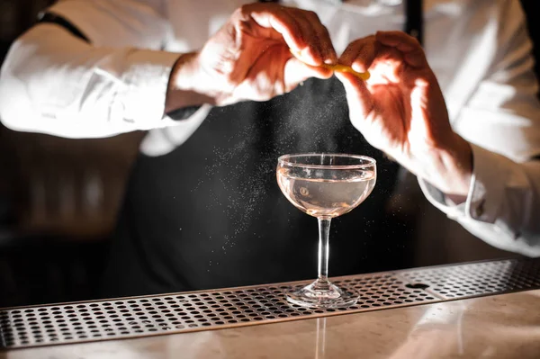 Barman mãos polvilhando suco de casca de laranja em um copo — Fotografia de Stock